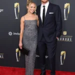 **Alt Text (SEO Optimized with Keyword):** *Sam Darnold and fiance Katie Hoofnagle pose together on the red carpet at the NFL Honors event, wearing formal evening attire and smiling for photographers.*