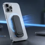 Modern smartphone with ultra-thin OhSnap5 magnetic grip attached, shown with soft magnetic glow on a clean tech desk